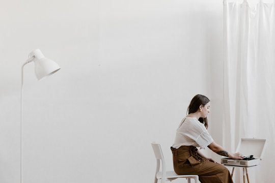stylish young woman putting a record on in a minimal white interior