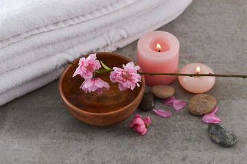 Obraz na płótnie Canvas cherry blossom sakura with wooden bowl ,towel, candle, stones on gray background