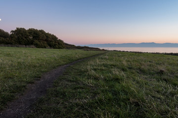 Fototapeta na wymiar trail on the grass field pointing towards the ocean at sunset