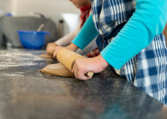 Kinder backen Kekse für Weihnachten, Junge rollt den Teig aus