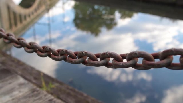 Close up of chain with toe path reflection water