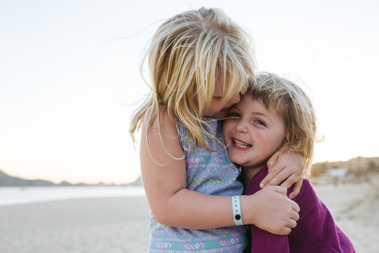 Two young girls enjoying each other on the beach at sunset