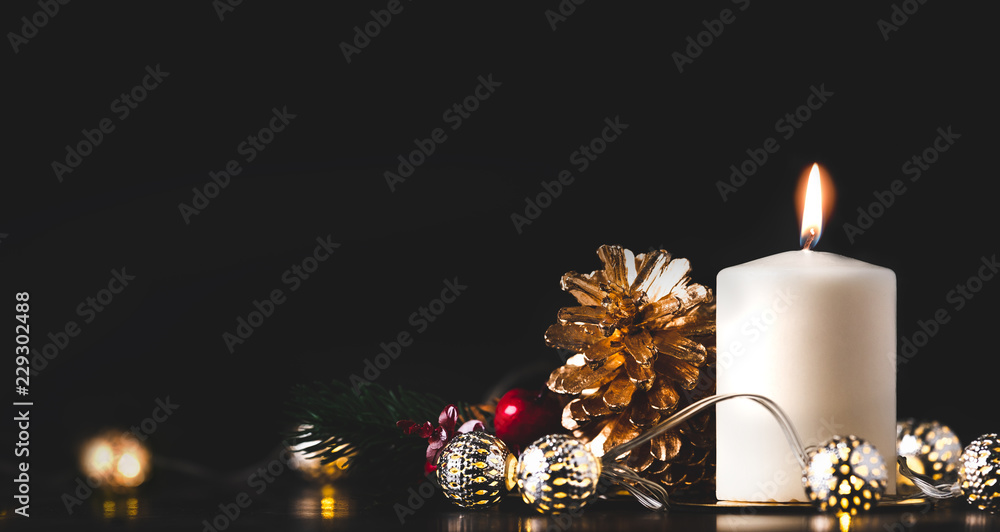 Poster christmas white candle with golden pine cone,mistletoe and light string glowing on black marble tabl