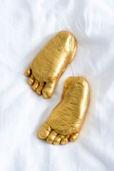 Golden baby feet imprint on fabric background