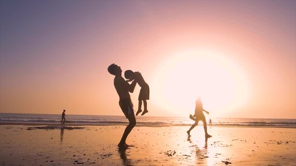 Ultra slow motion - silhouette of father and son playing together in the beach at sunset