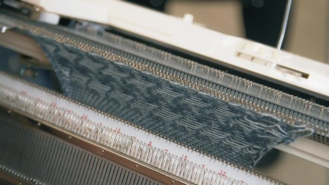 Close up female hands working on modern knitting machine. Knitting yarn on weaving machine. Knitting machine production cloth