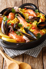 Spanish paella with shrimps, mussels, fish, and baby octopus close-up in a frying pan. vertical