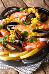 Delicious Spanish paella with seafood and fish close-up in a pan. vertical