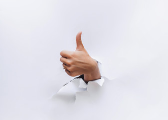 Thumbs up sign. The hand came out through the hole in white paper and shows finger up. Like, cool,...