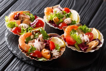 Beautiful seafood cocktail salad of shrimp, baby octopus, mussels, squids and scallops with vegetables in sea shells close-up. horizontal