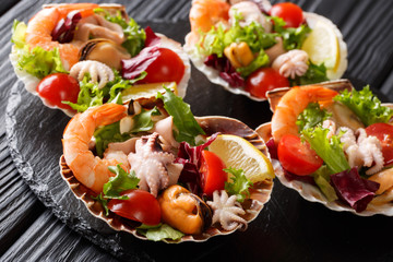 Dietary healthy seafood salad of shrimp, baby octopus, mussels, squids and scallops with vegetables in sea shells close-up. horizontal