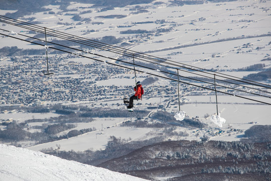 A  snowboarder on chair lift in ski field