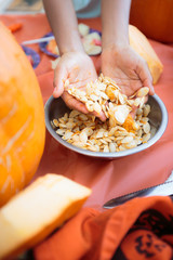 Hands in a bowl of raw pumpkin seeds