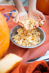 Hands in a bowl of raw pumpkin seeds