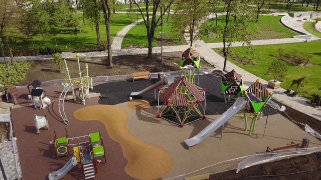 Aerial footage of luxury kids playground in suburban park. Park reconstruction for children. Workers laying colorful rubber crumb on the ground. Construction site.