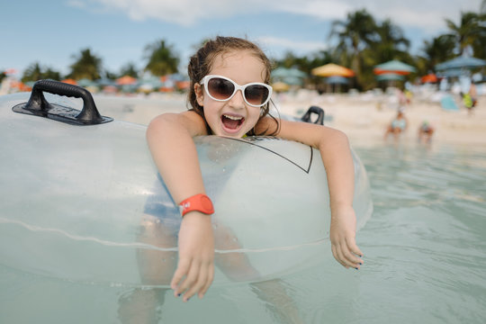 Cute young girl in sunglasses having fun with an intertube in water