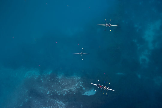 Group of sportsmen kayaking on blue water surface.