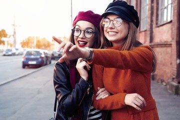 Outdoors fashion portrait young pretty best girls friends in friendly hug. Walking at the city....