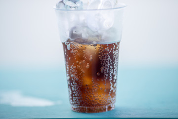 A close-up view of a glass of soft drink. Put on the wooden floor, the back is a bright sky, beautiful natural wallpaper.