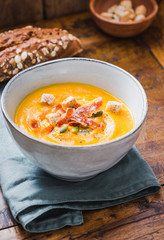 Pumpkin cream soup bowl.Pumpkin soup with pumpkin seeds and wooden background.