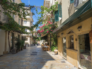Corfu old town cobble stone street with cafe and flower garlands, summer sunny day, Corfu island, Ionian islands, Greece