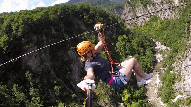 Woman canopying over the forest on zipline in Slovenia.