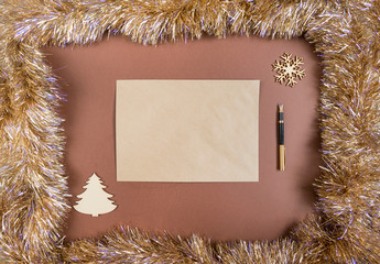 place for inscription on a brown background framed by tinsel, Christmas tree, snowflake, fountain pen
