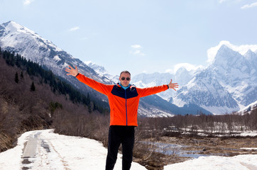 man in a red jacket with outstretched arms on a background of mountains ,Caucasus mountains 2018