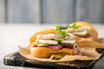 Sandwich with herring fillets, onion, eggs, pickled cucumber on parchment paper on board....
