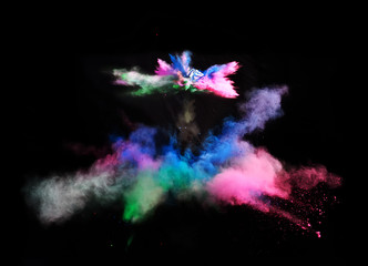 Multi Colored forms of powder paint and flour combined  together explode in front of a black...