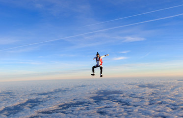 Skydiver is in the sky above clouds.