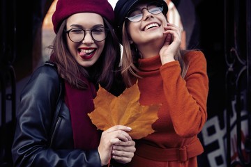 Outdoors fashion portrait young pretty best girls friends in friendly hug. Walking at the city....