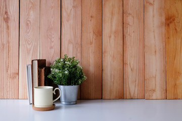 Copy space office desk books, coffee mug and plant decoration on white table and wood wall.