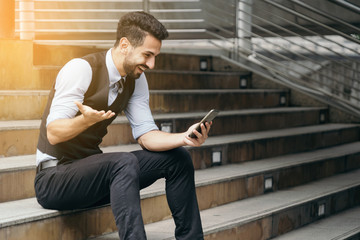 portrait of smart business man use smartphone technology outdoor and feeling happy