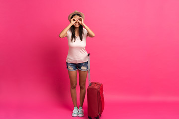 Woman traveler with suitcase on color background.