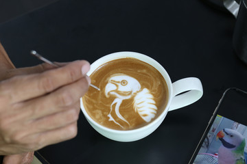 Professional of coffee latte barista making pattern the parrot in a cup with bar interior background