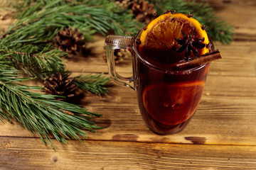 Christmas mulled wine with spices and fir tree branches and cones on wooden table
