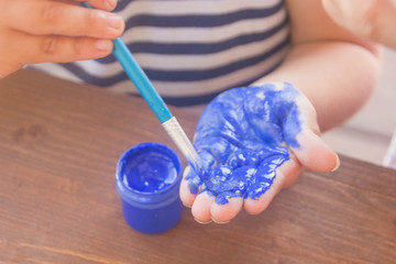 Paint your hand with green paint. A child paints a palm paint, close-up.