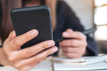 Closeup image of a woman holding , using and looking at smart phone while working