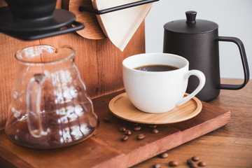 A cup of drip coffee and equipment on vintage wooden table