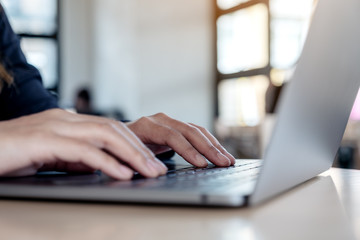 Closeup image of hands using and typing on laptop keyboard on table