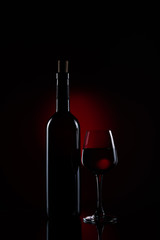 A bottle of red wine with a half full wine glass using stripbox for rim light effect