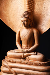 Buddha in a meditation pose, under protection of the king of nag - Mukalinda. Figure isolated on a black background. © Dymov