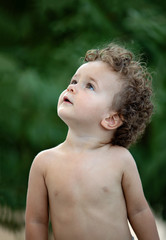 Beautiful baby with curly hair in the garden