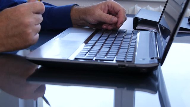 Man Hands Playing Nervous with a Pencil Over Laptop Keyboard