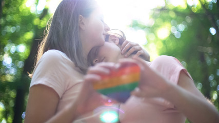 Lesbians in love embracing, holding rainbow heart, concept of lgbt rights