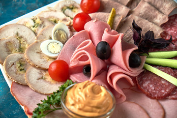 Cold smoked meat plate with prosciutto, salami, bacon, pork chops, cheese and olives on gray stone background.