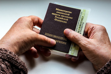 Woman's hand holding russian pension certificate. Russian translation - Ministry of Social...