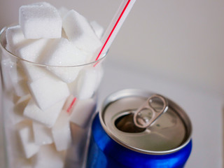 conceptual still life image of glass with straw full sugar cubes and soda refresh drink  in...