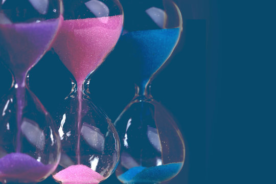 colored hourglass on a blue wall background, toned image